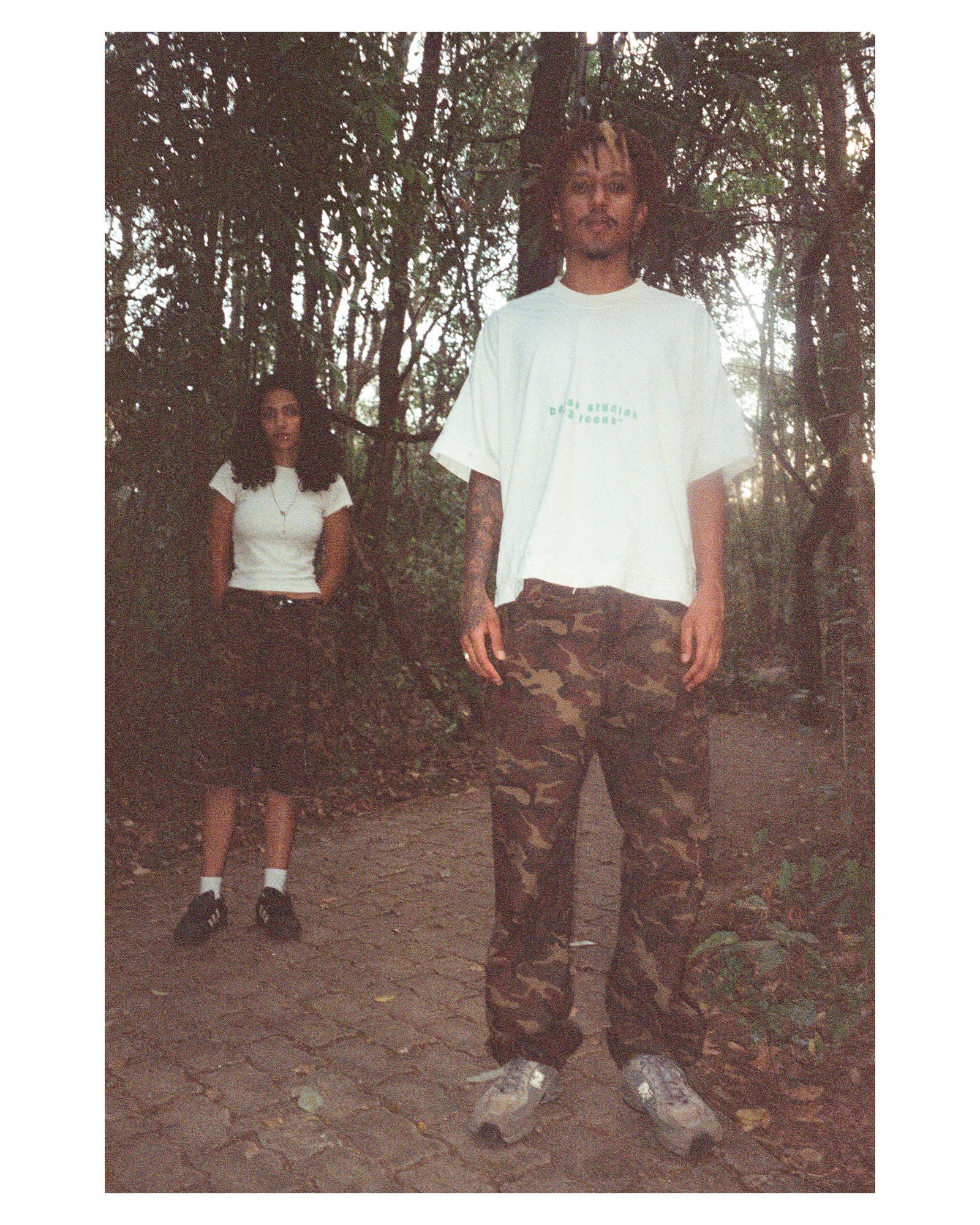 Modelo de camiseta branca e calça camuflada em uma trilha na mata